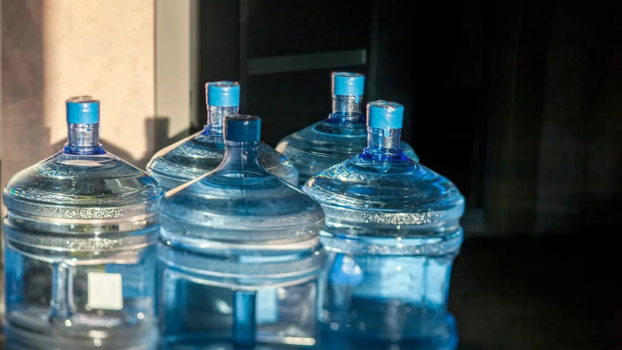 Varios bidones de agua de 20 litros apoyados en un ambiente interior